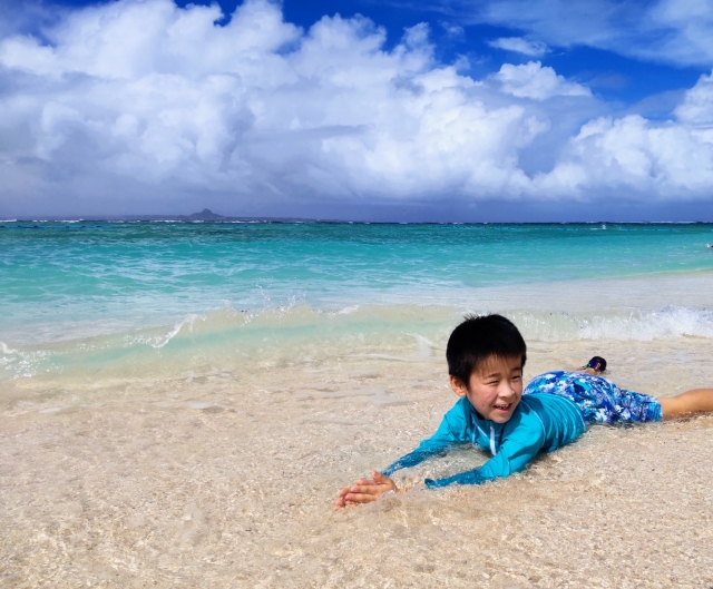 沖縄の海の波打ち際で遊ぶ子供